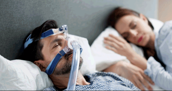 Man with sleep apnea wearing CPAP machine