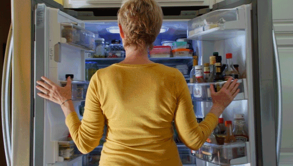 Woman looking for a snack in fridge - food cravings