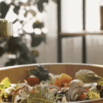 Olive oil being poured into a bowl full of salad
