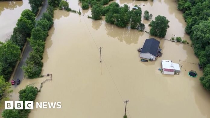 A house is under water after flooding. The water surrounding it is brown.