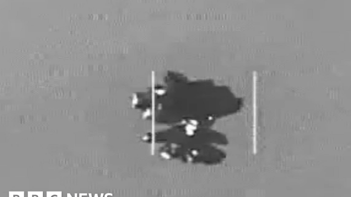 An object which is thought to be an Unidentified Anomalous Phenomena in the center of the frame. The image is in black and white and is grainy.