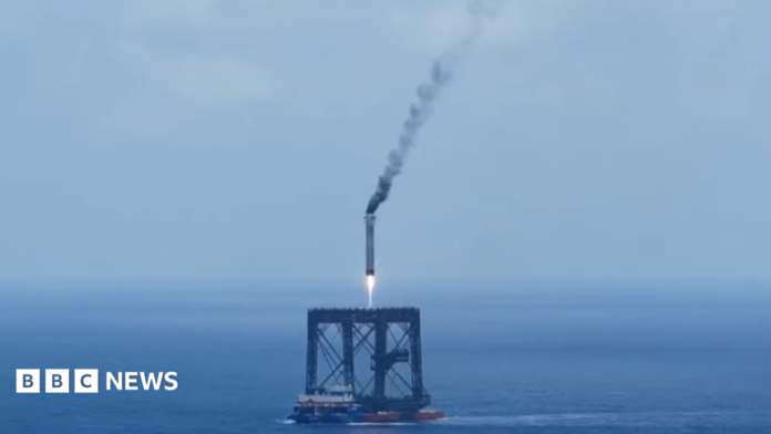 A screengrab of  a Long March 10B booster rocket landing on a recovery platform.