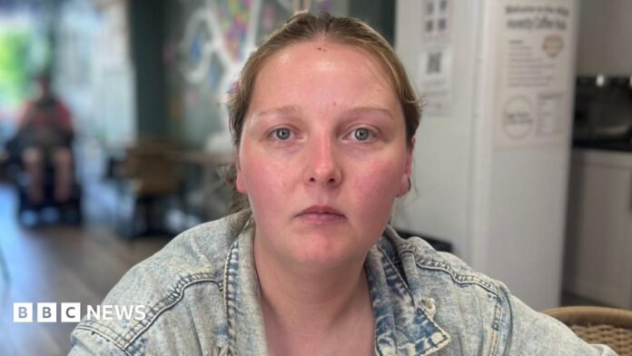 Susan has blonde hair tied back and is wearing a blue denim jacket.