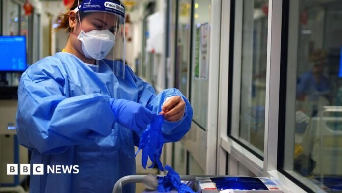A nurse puts on PPE in a ward for Covid patients