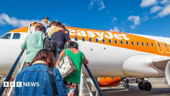 People climb the stairs onto an easyJet orange and white plane.