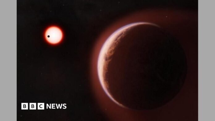 An artist's impression of exoplanet LHS 1140b, a large reddish-brown rocky planet filling the foreground, edged with a faint blue-white atmospheric glow. In the dark background, a small red star glows brightly, with a second, closer planet shown as a tiny black silhouette crossing in front of it