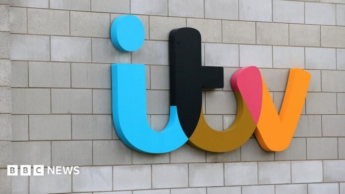 Mobile phone with an ITV 1 logo in black and yellow on the screen and blurred images of a streaming service in the background