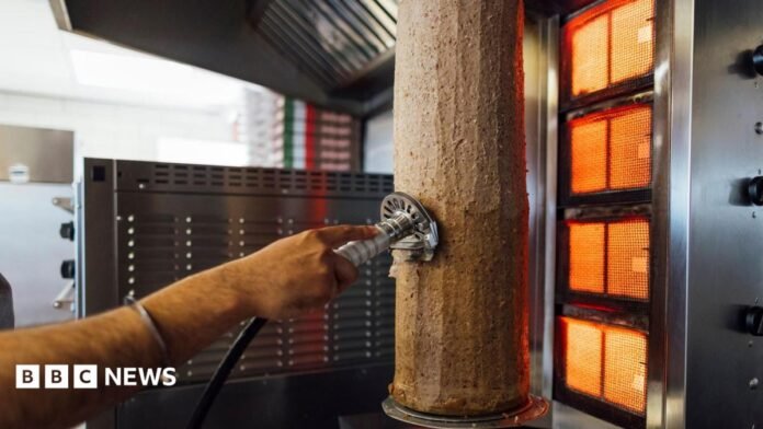 A meat doner kebab on a skewer in a shop