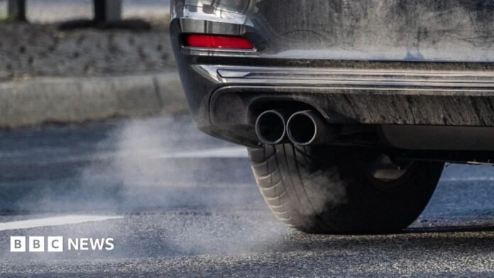 A car's exhaust pipe is in view with some of the car also shown.