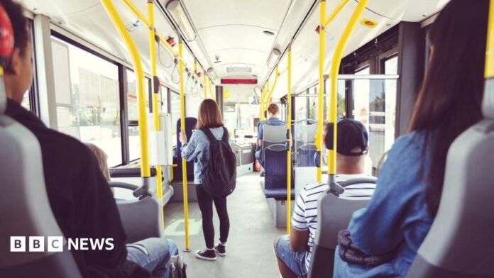Young man wearing black hoodie, grey t-shirt and headphones uses his bus pass