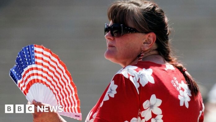 Woman wearing sunglasses holds fan in colours of US flag