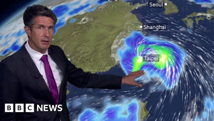 A weather presenter stands in front of a screen showing heavy rains over Taiwan