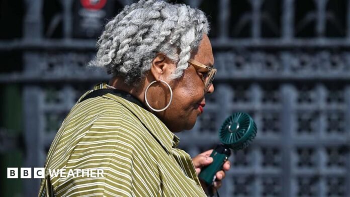 A woman uses an electronic fan to keep cool as temperatures soar in the United Kingdom