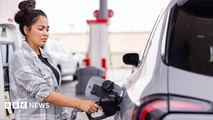 Woman wearing a grey shirt fills up her car at a gas station