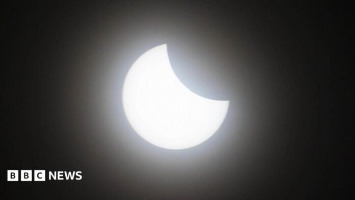 An eclipse, with the moon covering the upper right portion of the sun.