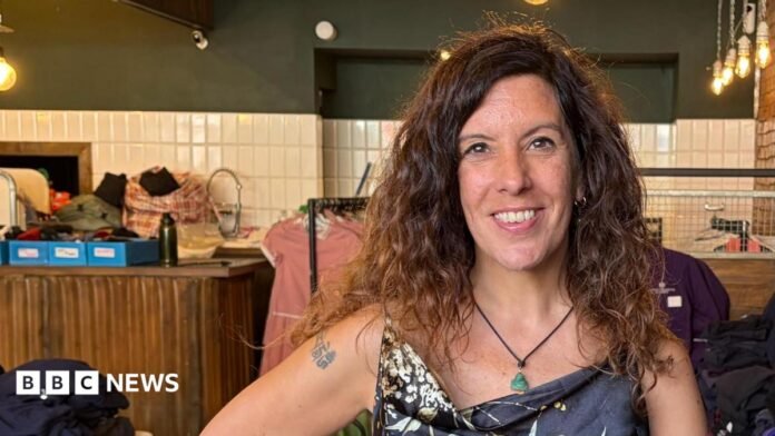 Cristina is smiling at the camera, in the background are different coloured school jumpers.