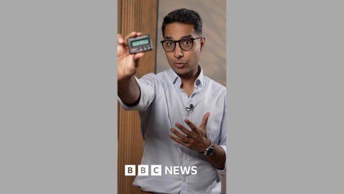 A man holding a pager towards the camera.