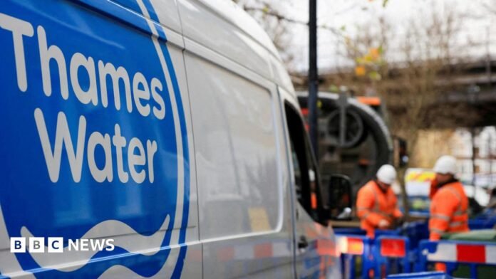 A shot of a Thames Water van. In the background there are two men wearing hi-vis clothing and hard hats and standing in an area that is boarded off by blue fences. 
