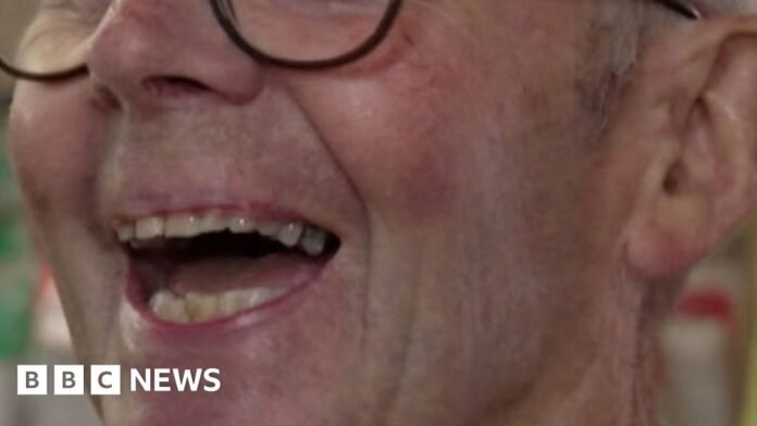 Patrick Meredith, he's a white man with glasses and grey hair. He's mid laugh, looking just away from the view of the camera.